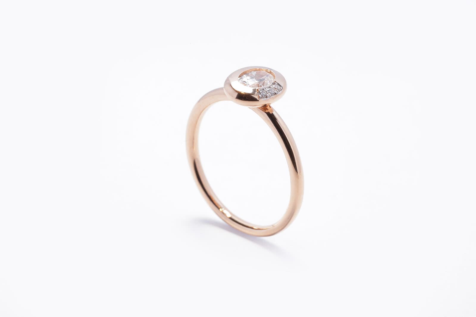 A sleek rose gold ring featuring an oval center diamond